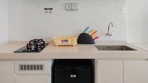A modern kitchen with a gas stove, a black dishwasher, and a sink. - Cozy Living and Comfort Studio at Sky House BSD Apartment (Pagedangan)