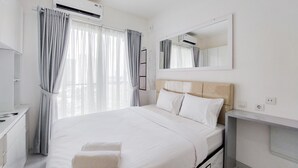 A modern hotel room with a large bed, a bedside table, a mirror, and an air conditioning unit. - Cozy Living and Comfort Studio at Sky House BSD Apartment (Pagedangan)