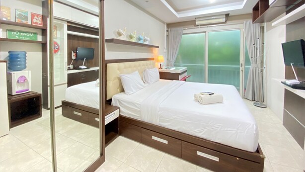 Une chambre d’hôtel moderne dotée d’un grand lit, d’un placard vitré, d’une table de chevet avec une lampe et d’un téléviseur.