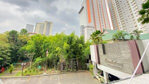 Un hôtel au design moderne, avec une entrée imposante, une allée bordée de portails et une végétation luxuriante en premier plan.