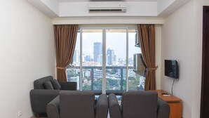 Ein modernes Wohnzimmer mit großem Fenster, einem Flachbildfernseher und einem Sofa.