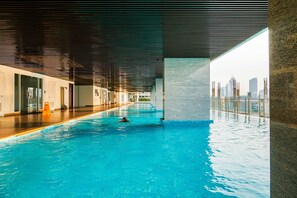 Ein beheiztes Hallenbecken mit Blick auf die Stadt, ein Holzboden und ein modernes Decken design.