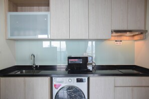 Une cuisine compacte équipée d’un lave-linge intégré, d’un four à micro-ondes et d’un évier.