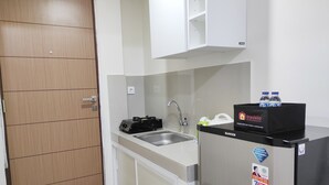 A compact kitchen with a sink, a refrigerator, and a microwave. - Simply Homey Studio at Vida View Apartment (Makassar)