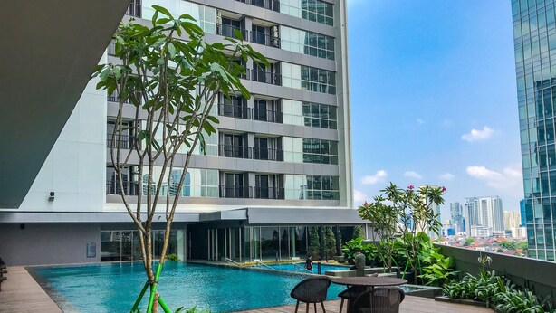 A rooftop pool area with a view of a modern building and city skyline. - Stunning Studio at Ciputra World 2 Apartment (Jakarta)