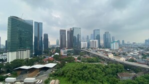 A cityscape with modern high-rise buildings, a highway, and surrounding greenery. - Stunning Studio at Ciputra World 2 Apartment (Jakarta)