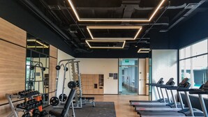 A gym with treadmills, weight machines, and a mirrored wall. - Stunning Studio at Ciputra World 2 Apartment (Jakarta)