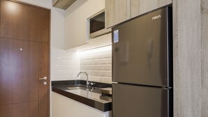 A modern kitchen with a stainless steel refrigerator, a black countertop, and white cabinets. - Stunning Studio at Ciputra World 2 Apartment (Jakarta)
