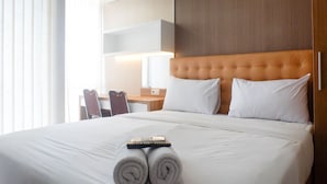 Habitación de hotel con una cama grande, cabecera de madera, un escritorio con silla y una lámpara.