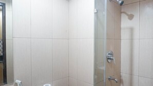 Un baño con inodoro, ducha y espejo.