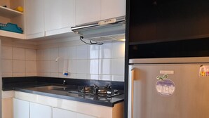 Eine Küche mit weißen Schränken, einer schwarzen Arbeitsplatte, einem Edelstahl-Kühlschrank und einem Gasherd.