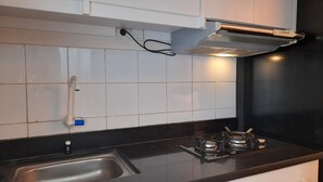 Eine Küche mit schwarzer Arbeitsplatte, Spüle aus Edelstahl, weißen Schränken und einem Gasherd.