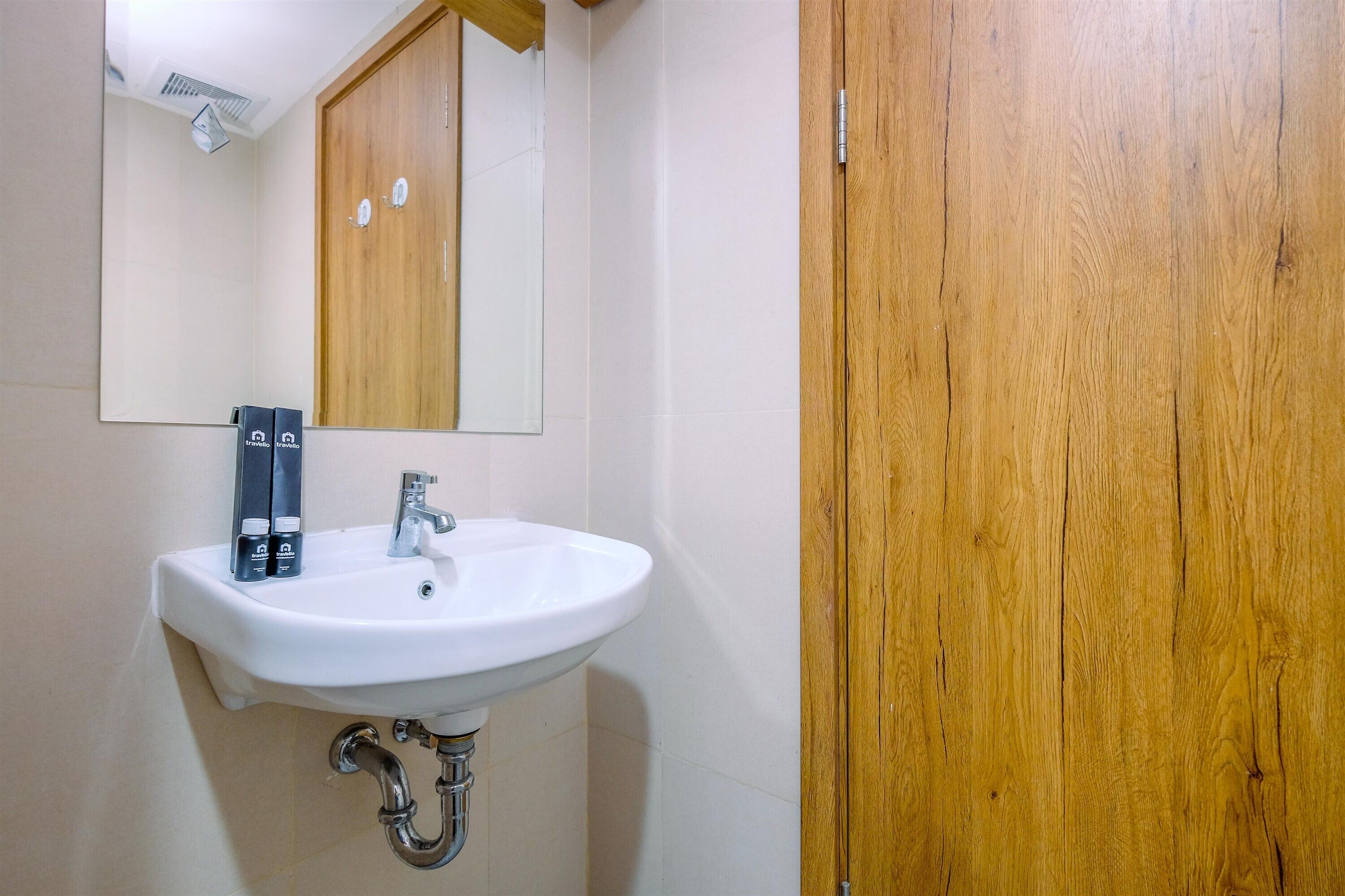 Un baño con un lavamanos blanco, un espejo y puertas de madera.