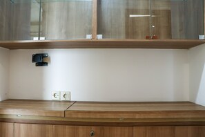 Une pièce comprenant un meuble en bois, une étagère en verre et une prise électrique fixée au mur.