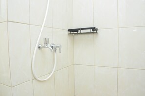 Bathroom features a wall-mounted faucet and a metal shelf unit.