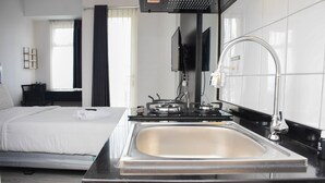 Una habitación de hotel moderna con una cama grande, un lavamanos integrado y un televisor de pantalla plana.