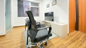 A modern office space with a black office chair, a desk with a flat-screen TV, and a window with blinds. - Modern and Well Furnished 2BR at Jarrdin near Cihampelas Walk (Bandung)