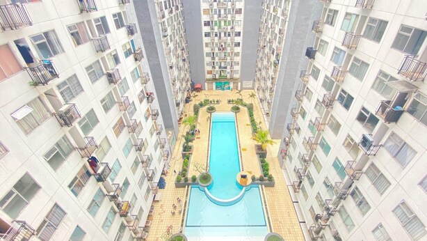 A high-rise residential building with a central swimming pool surrounded by greenery and balconies. - Modern and Well Furnished 2BR at Jarrdin near Cihampelas Walk (Bandung)