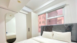 A bedroom with a bed, a mirror, and a window. - Modern and Well Furnished 2BR at Jarrdin near Cihampelas Walk (Bandung)