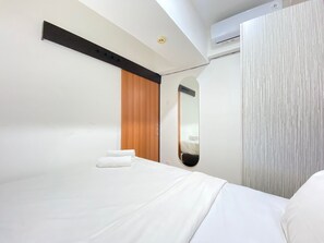 Une chambre d’hôtel moderne équipée d’un lit, d’une armoire en bois, d’un miroir et d’un appareil de climatisation.