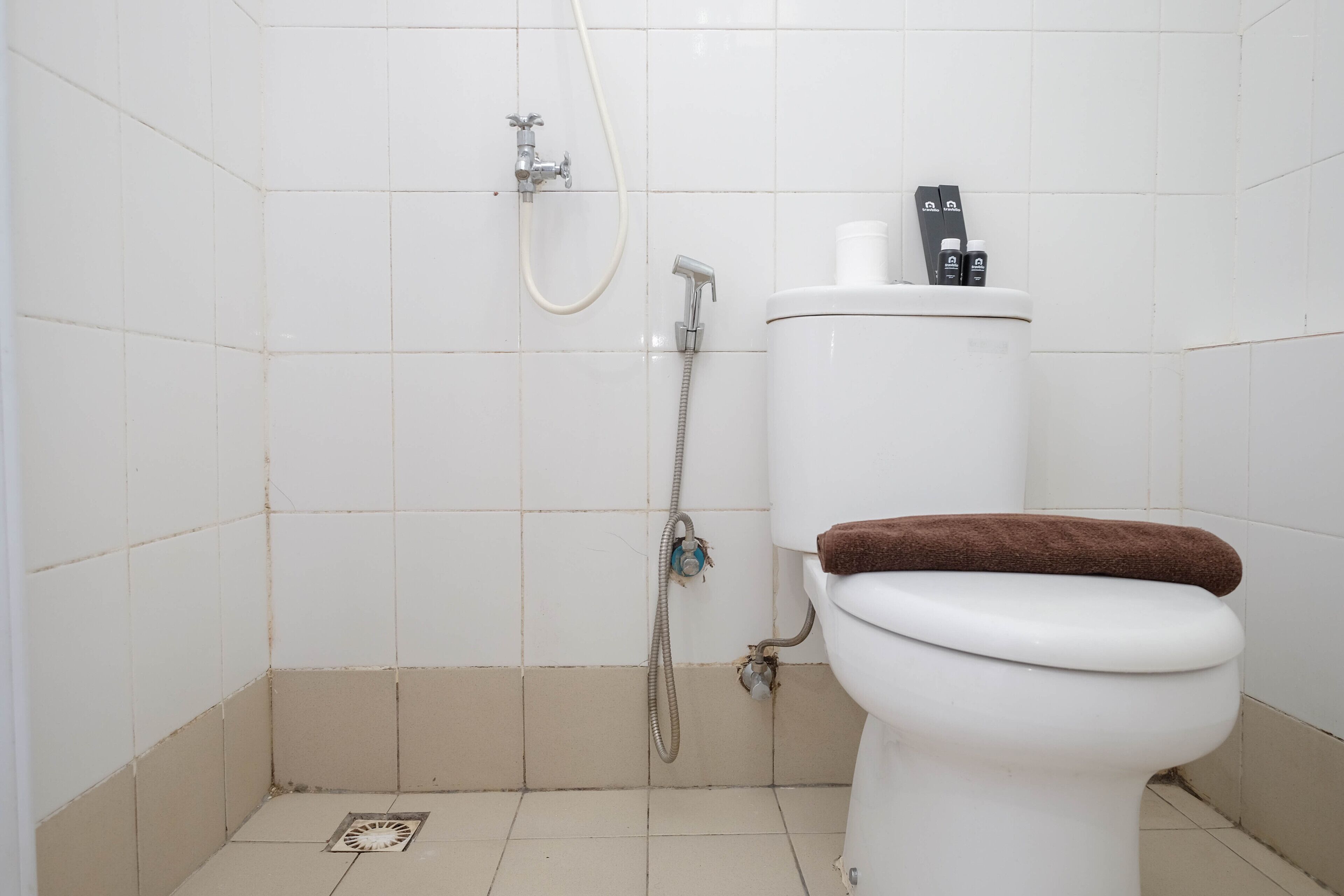 A small, clean bathroom with a toilet, a shower, and a toilet paper holder.