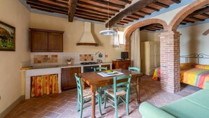 Une cuisine rustique avec des poutres apparentes, un coin repas avec une table et des chaises, et un espace de vie chaleureux avec un lit.