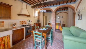 Une cuisine chaleureuse avec une table à manger, des chaises et un canapé vert.