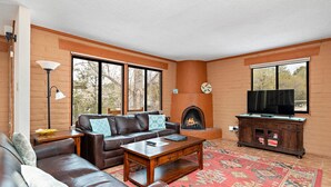 Una sala de estar con chimenea, televisor, sofá y mesa de centro.