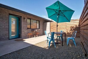 Relax on the patio with a table and chairs, shaded by a large umbrella.