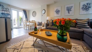 Un salon avec une table basse en bois, un canapé et un coin repas avec des chaises.