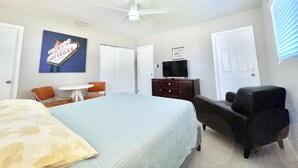 A bedroom with a bed, a desk, a chair, a dresser, and a ceiling fan.