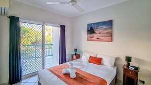 A hotel room with a bed, a painting on the wall, a window with curtains, a nightstand, and a heater. - Zen City Balcony ~ Outdoor Dining ~ Mindal Markets (Larrakeyah)