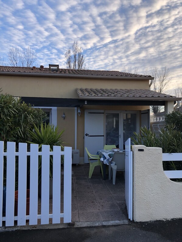 A house with a covered patio, a white picket fence, and a door with a glass panel.
