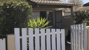 A residential building with a white picket fence, a tiled roof, and a door leading to a garage. - COMFORTABLE VILLA NEAR EUROPARK (Vias)