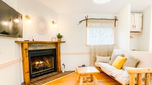 Una sala de estar con chimenea, muebles de madera y un sofá con cojines.