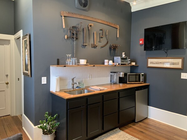 A modern kitchen with dark walls, a wooden countertop, and black cabinets.