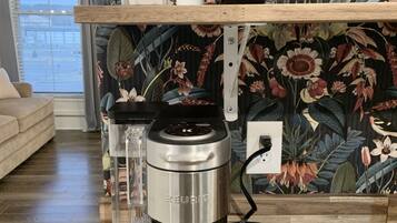 En Keurig-kaffemaskin står på en träbänkskiva med en blommig tapet som bakgrund.