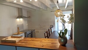 Une cuisine moderne avec un plan de travail en bois, un four encastré et un évier. On peut voir une orchidée en pot sur le plan de travail et un luminaire suspendu au-dessus.