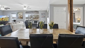 Een eetgedeelte met een houten tafel, zwarte lederen stoelen en potplanten.