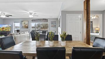 A dining area with a wooden table, black leather chairs, and potted plants.