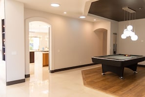 Enjoy a game of pool in this stylish room, featuring a pool table and a separate kitchen area with a sink and countertop.