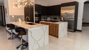 A modern kitchen with a central island, stainless steel appliances, and a unique chandelier. - Spectacular custom home with private pool (Las Vegas)