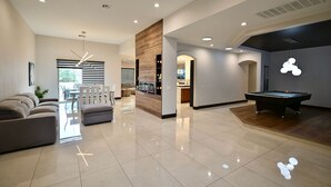 A modern living room with a pool table, a sofa, and a dining area. - Spectacular custom home with private pool (Las Vegas)