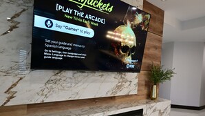 A television mounted on a marble wall displaying an advertisement for 'Yellowjackets' with instructions for changing language settings. - Spectacular custom home with private pool (Las Vegas)