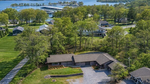 A residential area with a house surrounded by trees and a lake in the background. - Lakefront Retreat with Dock and Fire Pit (Gilbertsville)