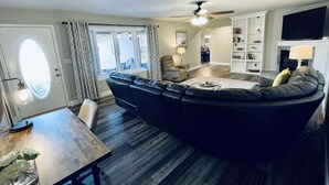 A modern living room with a sectional sofa, a dining table, and a fireplace. - Lakefront Retreat with Dock and Fire Pit (Gilbertsville)