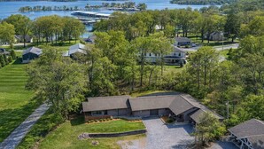 Een woonwijk met een huis, omgeven door bomen en een meer in de verte.