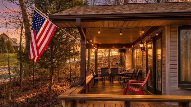 Een houten terras met buitenmeubilair, een Amerikaanse vlag en een overdekte veranda.