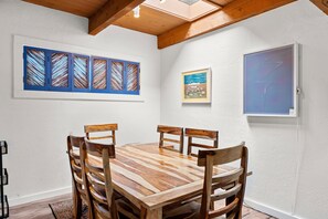 A dining area with a wooden table and chairs, a skylight, and artwork on the walls.