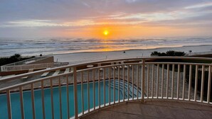 Ein Poolbereich mit Blick auf den Sonnenuntergang über dem Meer.